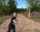 alicia is standing in front of a roughed in driveway on wooded land smiling and giving the thumbs up
